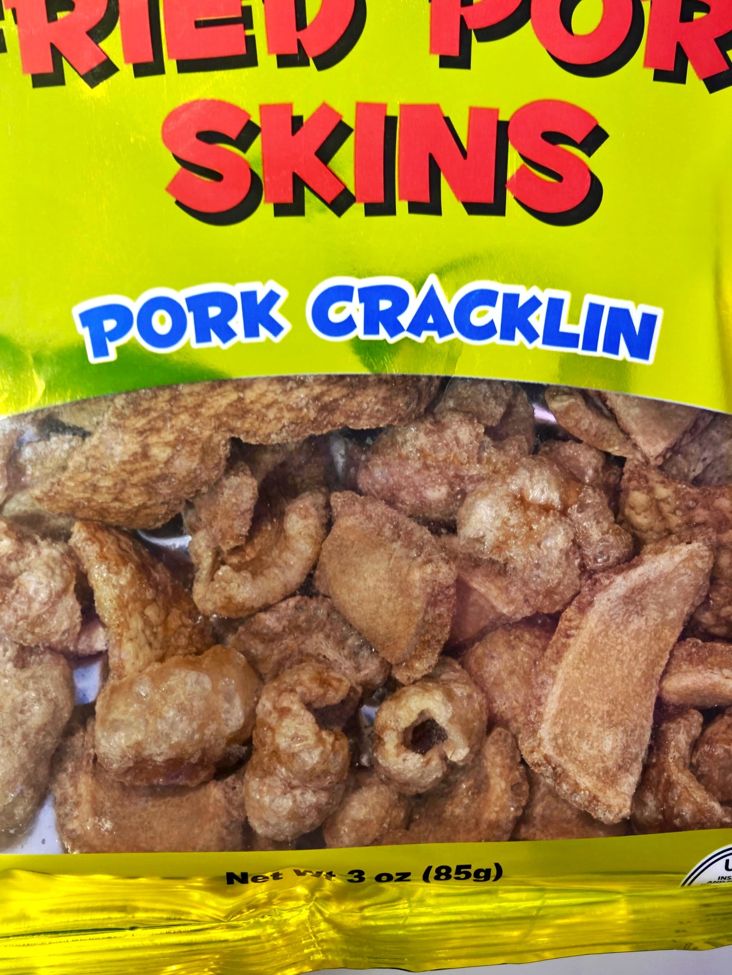Packaged pork cracklin with yellow background and text